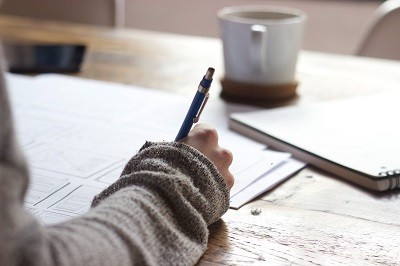 Eine Person arbeitet an verschiedenen Papieren und macht sich handschriftliche Notizen.