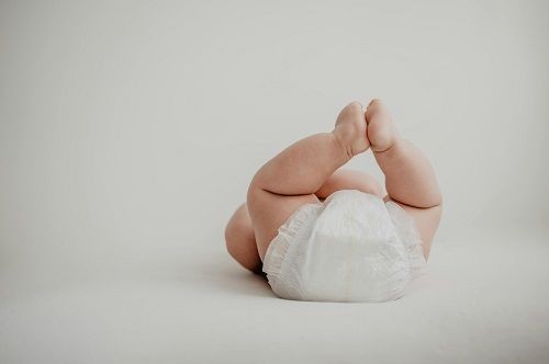 Ein Baby liegt auf dem R&uuml;cken, streckt die F&uuml;&szlig;e in die H&ouml;he und bringt die F&uuml;&szlig;e in der Luft zusammen. Von dem Baby sind nur der Po in einer Windel, die Beine und F&uuml;&szlig;e  sowie kleine Teile der Arme zu sehen.  