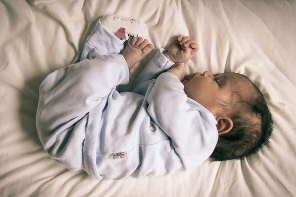Ein schlafendes Baby liegt in Seitenlage auf einer wei&szlig;en Matratze.