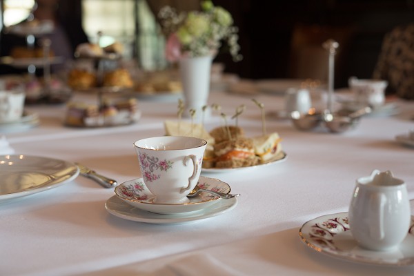 Zum Nachmittagstee gedeckter Tisch mit blumenverziertem Geschirr.