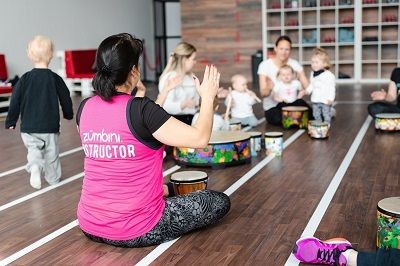 Kursleitung mit Teilnehmenden Eltern und Kindern in einer Sporthalle