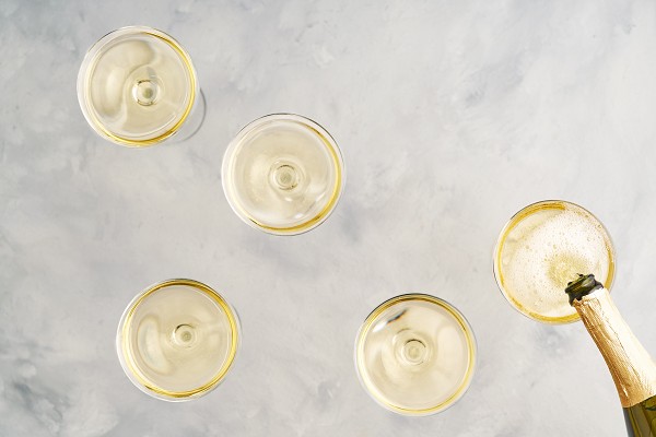 F&uuml;nf gef&uuml;llte Weingl&auml;ser von oben. in das Glas ganz rechts wird gerade Schaumwein eingeschenkt.  