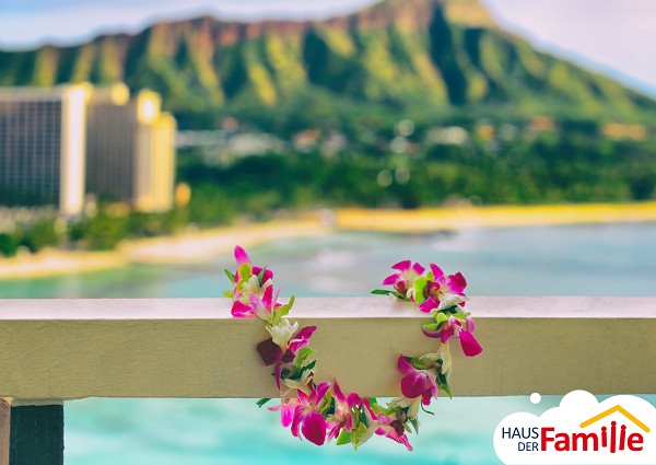 Berge in Hawaii im Hintergrund, eine Girlande aus Blumen im Vordergrund.