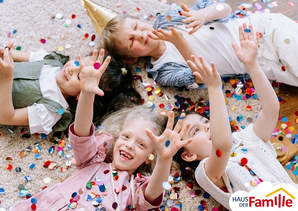 Kinder liegen auf dem Boden und spielen mit Konfetti